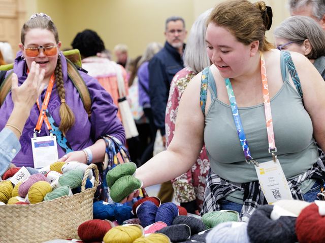 Shoppers picking out yarn from baskets at Sample It