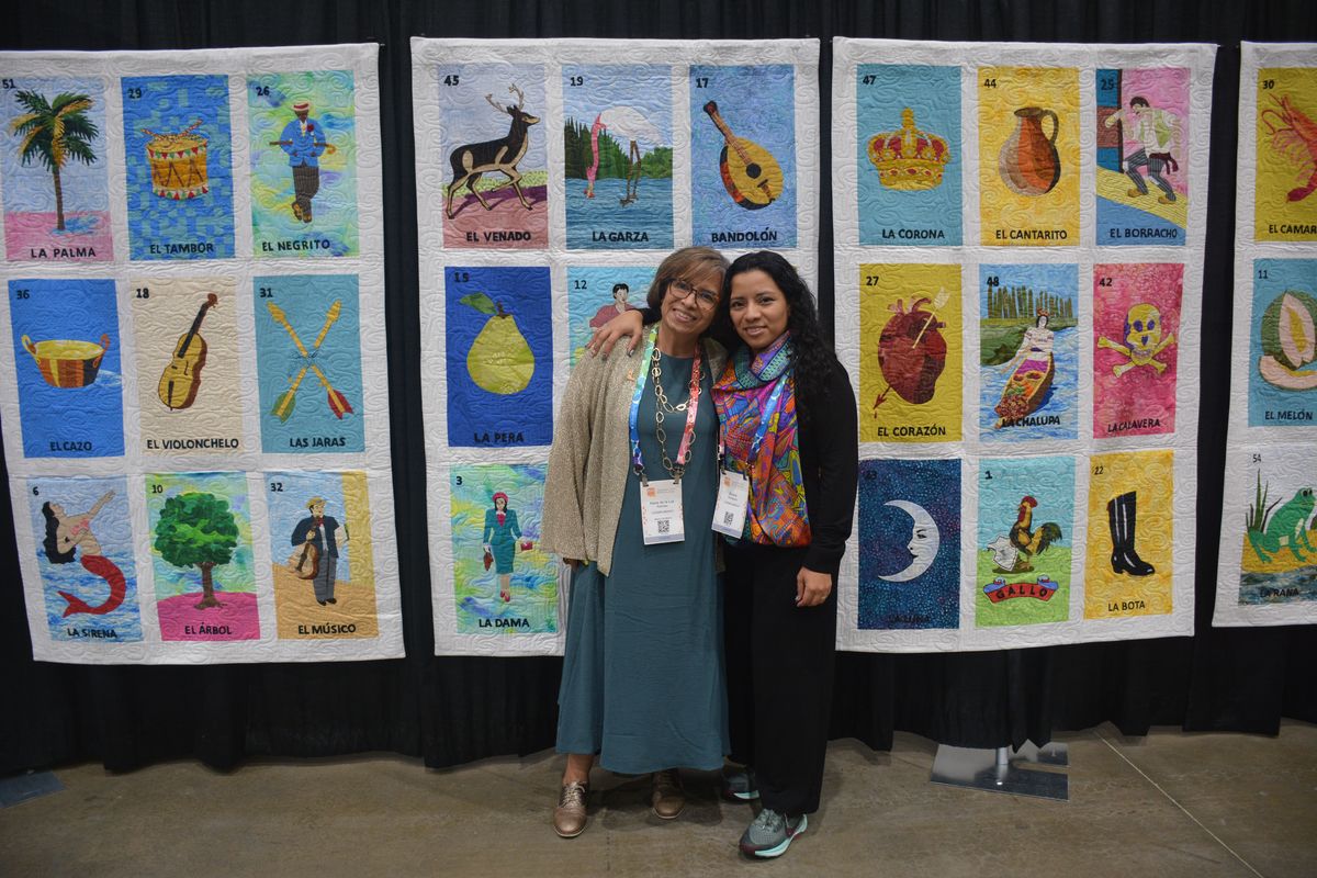 Two attendees in front of the Loteria quilt display