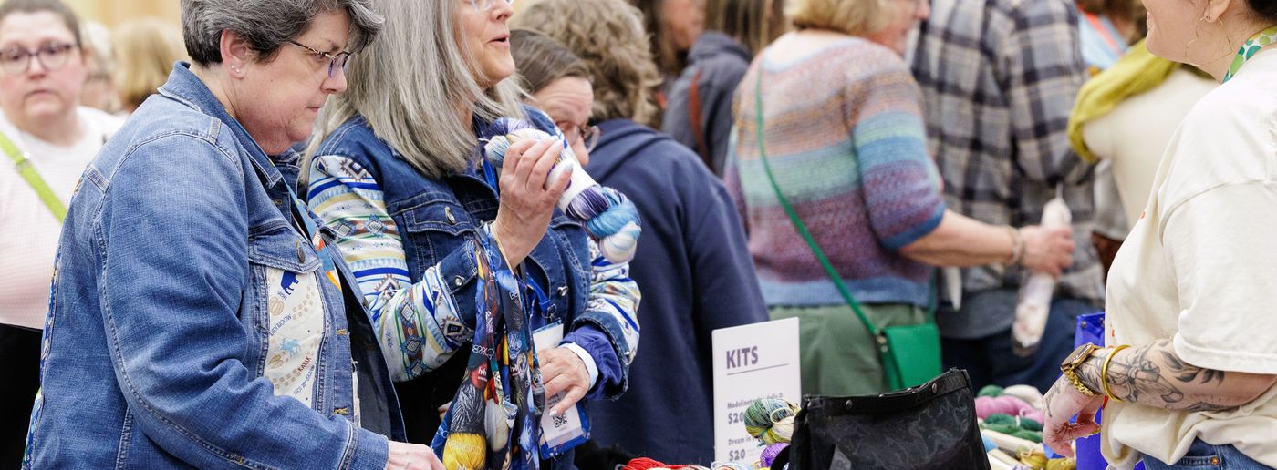 Buyers examining yarn and kits at the Sample It tables