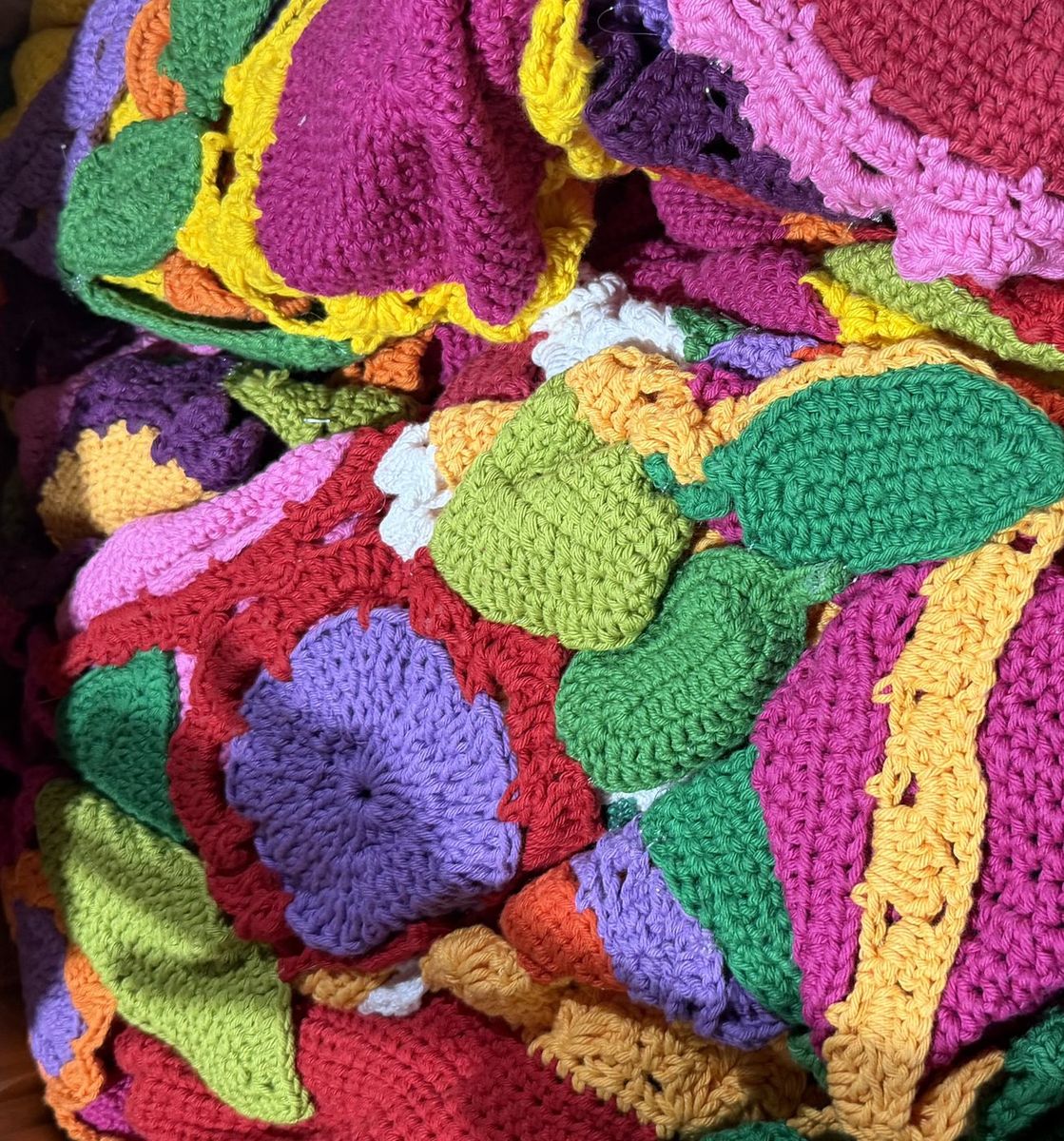 Detail of the crochet installation: dozens of hand-crocheted shapes in pink, green, purple, orange and yellow C&iacute;rculo cotton yarn